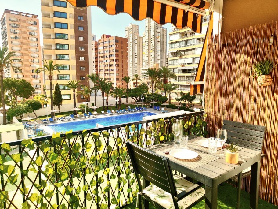 Balcon du studio avec table pour deux personnes et vue sur la piscine de la résidence et les gratte-ciels de Benidorm