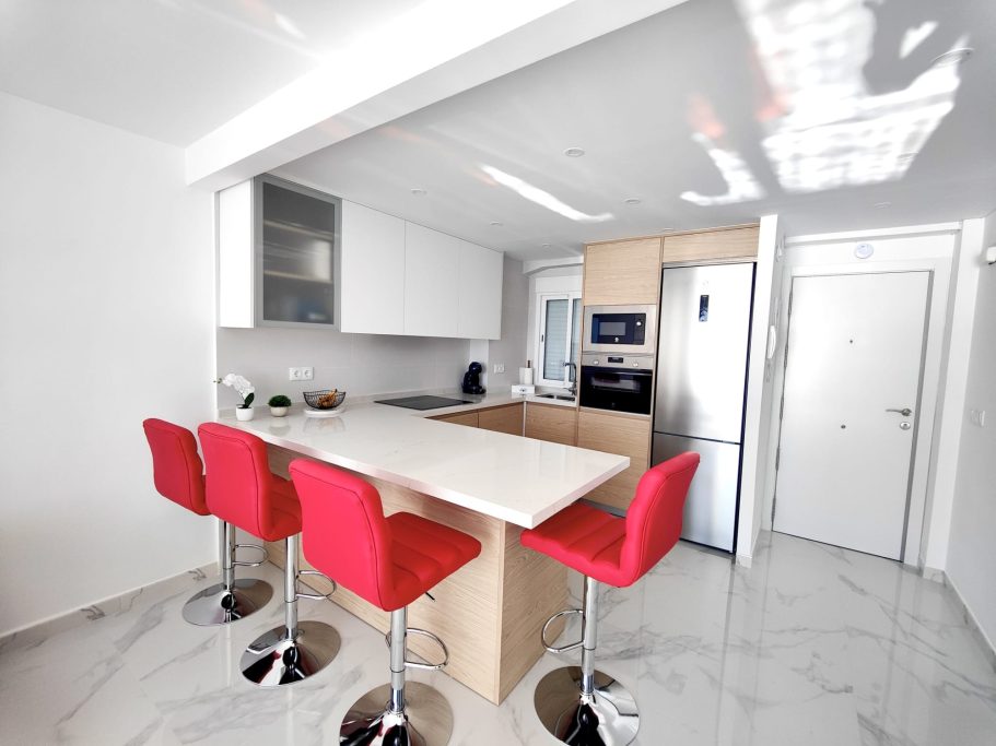 Cuisine moderne avec îlot central Cuisine moderne avec îlot central et tabourets rouges – appartement Veracruz Collection Signature Benidorm