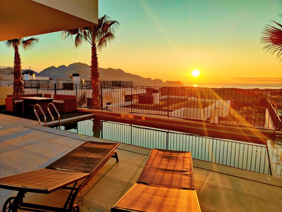 Piscine privée chauffée avec vue spectaculaire, transats et salon de jardin au lever du jour.