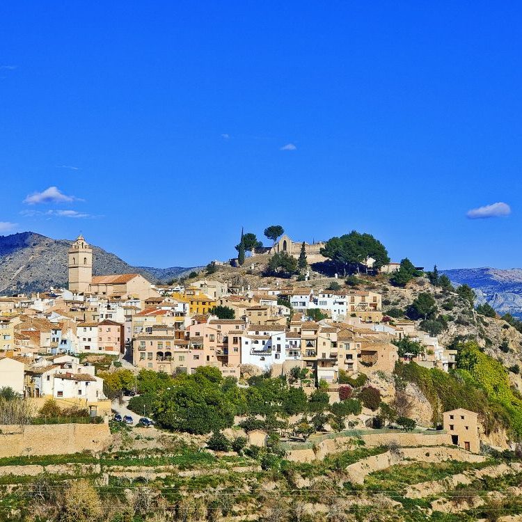 Photo panoramique des hauteurs de Polop, montrant l’église, le village et le Mont Poig, offrant un cadre authentique et paisible.