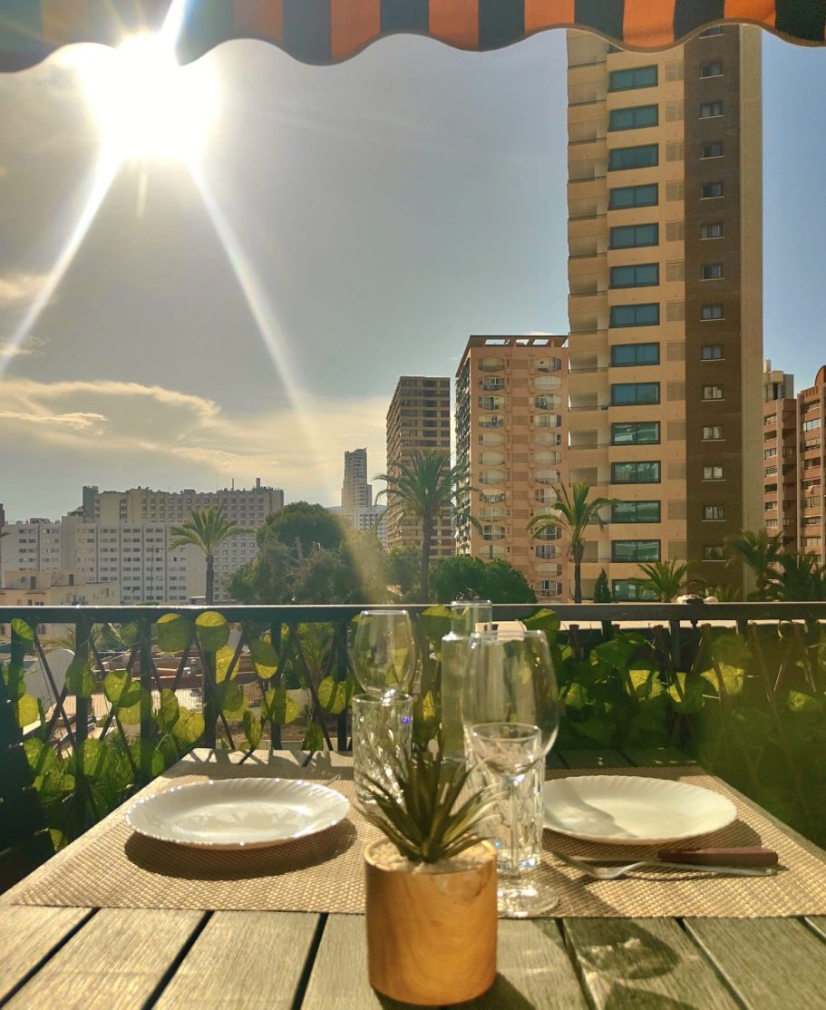 Table dressée sur le balcon du studio avec vue sur les gratte-ciels de Benidorm sous le soleil de fin d'après-midi