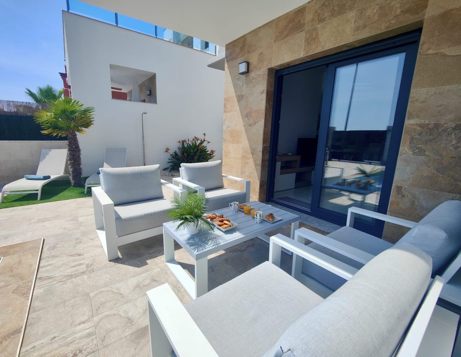 Salon de jardin avec petit déjeuner, piscine, transats et végétation méditerranéenne.